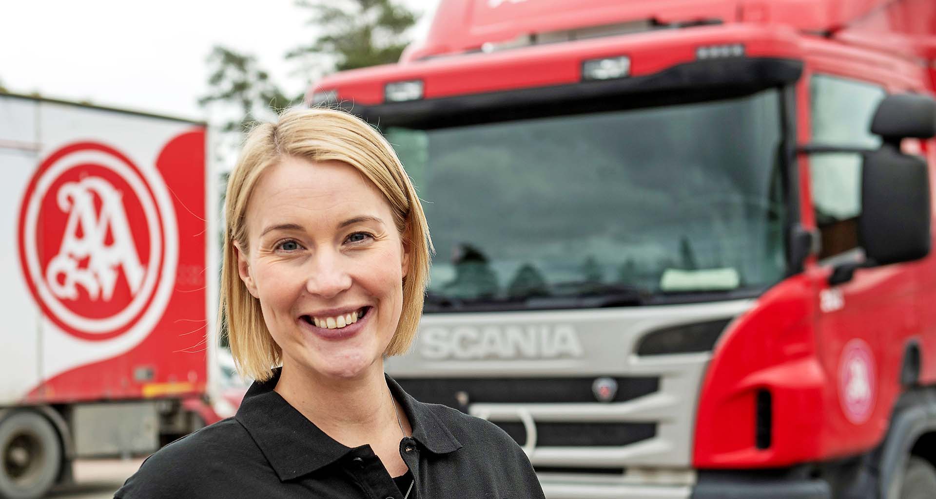 Kvinna framför AA Logistiks röda lastbil.. Pressbild